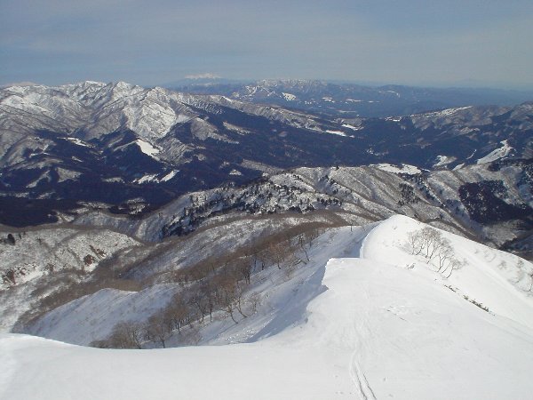 帰りは登ってきた雪稜を滑る。遠景は大日ヶ岳、御嶽山（中奥）。